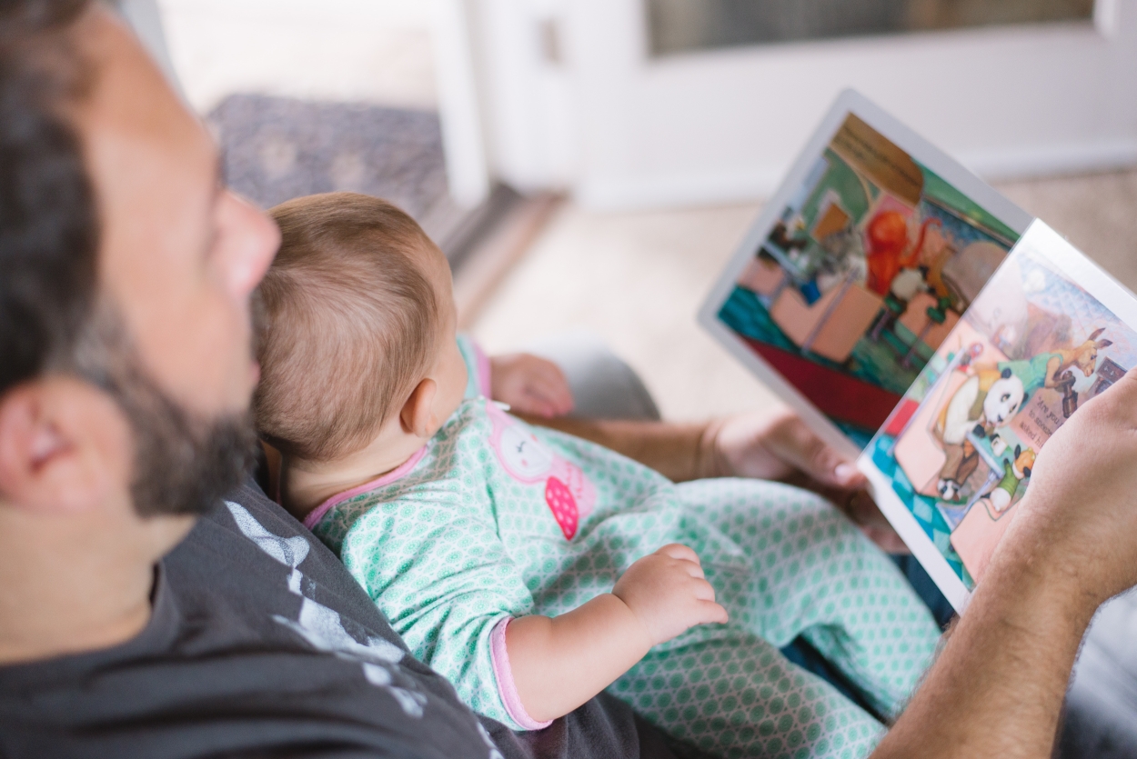 Tata czyta z niemowlakiem książeczkę